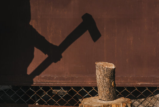 Photo of silhouette, shadow on wall of adult male strong lumberjack chopping log on stump with axe in forest against wall outdoors. Work concept. - Powered by Adobe