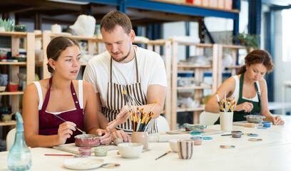 Experienced potter explains to students how to shape clay to make beautiful ceramic dishes