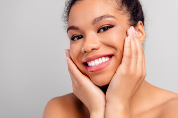 Smiling young woman with radiant skin, fresh makeup, and hair in a bun, expressing beauty and self...