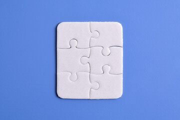 White puzzle pieces on blue background, top view. Space for text