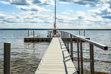 Sailing boats for rent moored to a pier in a yacht marina on lake. Vacations, recreational sailing, cruise.