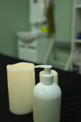 Soft candlelight illuminates a calming treatment room featuring a white lotion dispenser and a tranquil atmosphere, ideal for relaxation and wellness.