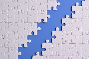 White puzzle pieces on blue background. Flat lay. Top view
