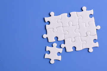 White puzzle pieces on blue background. Copy space for text, top view.