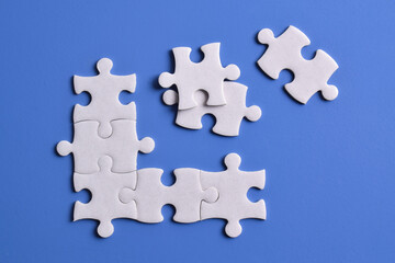 White puzzle pieces on blue background, top view