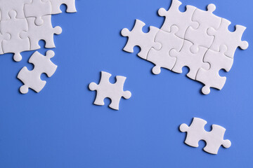 White puzzle pieces on blue background, top view