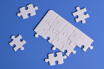 White puzzle pieces on blue background, top view