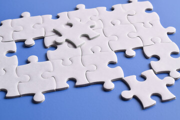 White puzzle pieces on blue background, top view