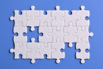 White puzzle pieces on blue background, top view