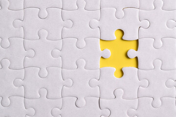 White puzzle with missing piece on yellow background, closeup