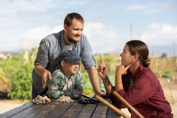 Family of farmers has fun talking at a wooden table after work. Farmers rest after planting seeds...