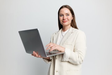 Professional woman engaged in remote work while holding a laptop in a bright, minimalistic office environment in the morning