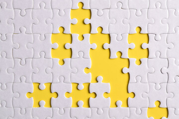 White puzzle with missing piece on yellow background, top view