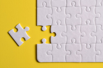 White puzzle pieces on yellow background. Flat lay. Top view