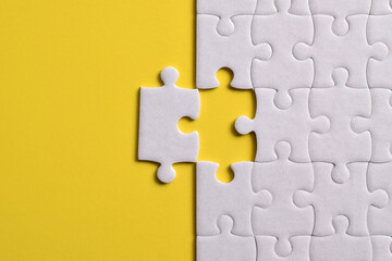 White puzzle pieces on yellow background. Flat lay. Top view
