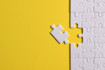 White puzzle pieces on yellow background. Flat lay. Top view