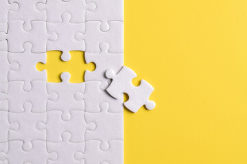 White puzzle pieces on yellow background. Flat lay. Top view