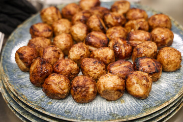Close-up of a plate full of grilled meatballs served on stacked ceramic dishes. Perfect for catering, restaurant menus, and food blog content.