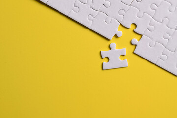 White puzzle pieces on yellow background. Flat lay. Top view