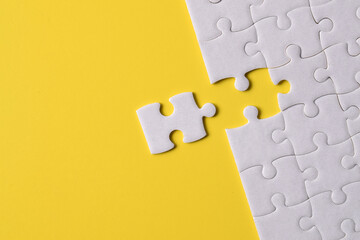 White puzzle pieces on yellow background. Flat lay. Top view