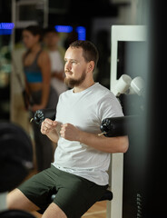 Man doing exercises for arms and shoulders. Gym client performing shoulder abduction to train...