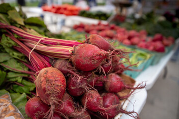 Bundles of red beets stacked and for sale on a table at a farmers market