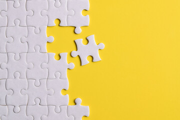 White puzzle with missing piece on yellow background. Flat lay. Top view