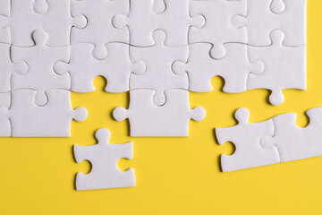 White puzzle with missing piece on yellow background. Flat lay. Top view