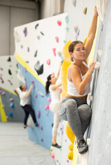 Young sporty woman training at bouldering gym without special climbing equipment