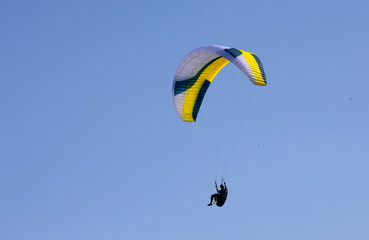 A flying paraglider against a blue sky background