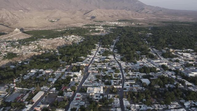 Drone footage at sunrise over Parras de la Fuente, showing urban layout and surrounding terrain under clear sky conditions, captured in stable 4K resolution with smooth tracking and overhead shots.