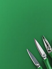Three silver scissors with green handles placed in the corner of a vibrant green background, offering ample copy space for design or text