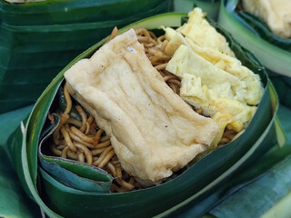 Fried noodles, tofu and omelettes, as well as side dishes, are served traditionally in banana leaves, showcasing Indonesian cuisine, usually served during the month of Suro, the Islamic New Year.	