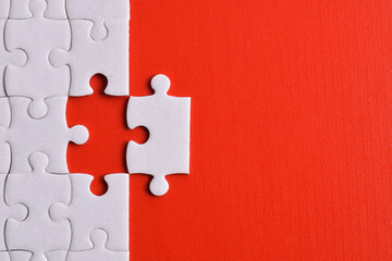 White puzzle pieces on red background. Flat lay. Top view