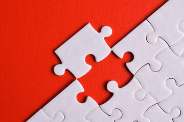 White puzzle pieces on red background. Flat lay. Top view