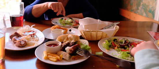 Served table with different restaurant dishes, Glasses of beer, bitter ale, snacks,shashlik, hamburger, salad, squid rings. Cafe. Process of eating