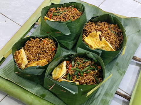 Fried noodles, tofu and omelettes, as well as side dishes, are served traditionally in banana leaves, showcasing Indonesian cuisine, usually served during the month of Suro, the Islamic New Year.