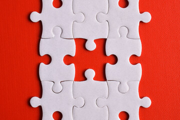 White puzzle pieces on red background. Flat lay. Top view