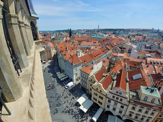 City street with a large crowd of people. There are many buildings with red roofs. A few of the...