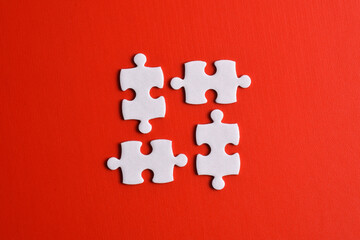Four puzzle pieces on red background. The concept of finding the right solutions in teamwork.
