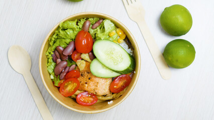 Disposable round bowl with healthy poke bowl with salmon. Cucumber. Rice. Beans. Tomato. Corn and...
