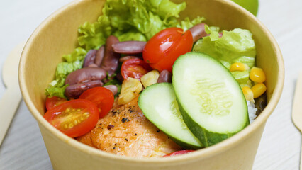Grilled salmon, rice, cucumber slices, cherry tomatoes, lettuce, beans, and corn combine in a...