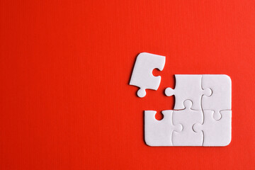 White puzzle pieces on red background. Flat lay. Top view