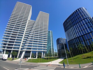 Large building with a white facade sits in front of a green grassy area. A car is parked in front...
