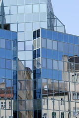 Fototapeta premium This image depicts the glass facade of a modern building, in which the surrounding buildings are reflected.