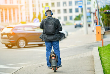 Man rides electric unicycle along city sidewalk on sunny day, personal urban transportation, modern eco-friendly commuting alternative. Unicyclist with backpack commuting on electric one wheel vehicle