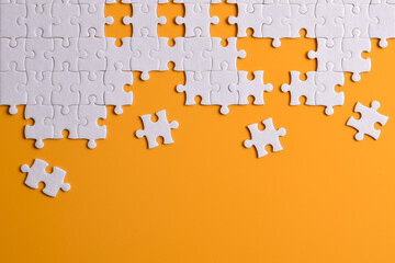 White puzzle pieces on orange background. Flat lay. Top view