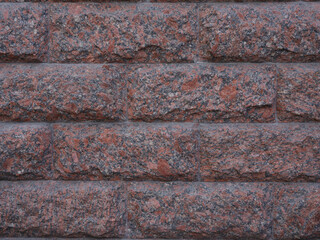 Close-up surface of red and black facing granite tiles in form of rectangular bricks for construction backgrounds.