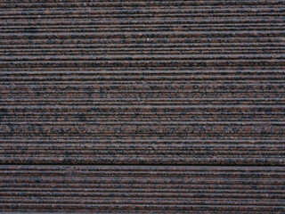 Close-up surface of striped ribbed red and black facing granite tiles for construction backgrounds