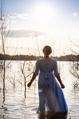 Water nymph. Lake and sunset. Woman standing in water. Woman in a blue dress. Blue water, beautiful nature and view. Mavka